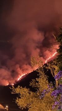 a fire burns on a hillside at night
