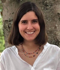 a woman smiling in front of a tree